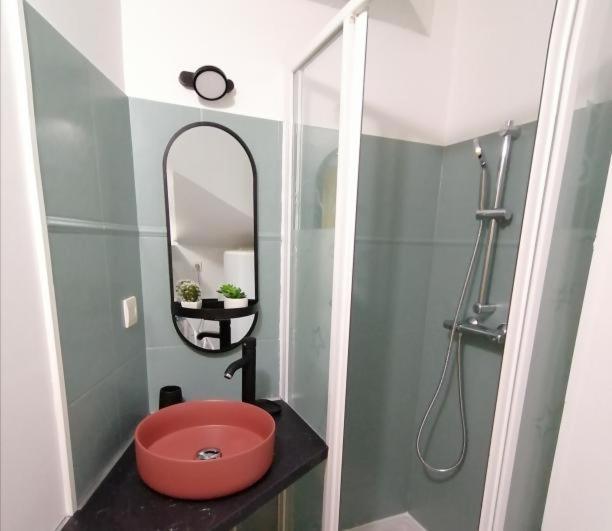 La salle de bains est pourvue d'un lavabo rouge et d'un miroir. dans l'établissement Vannes: charmant studio sur le port, à Vannes