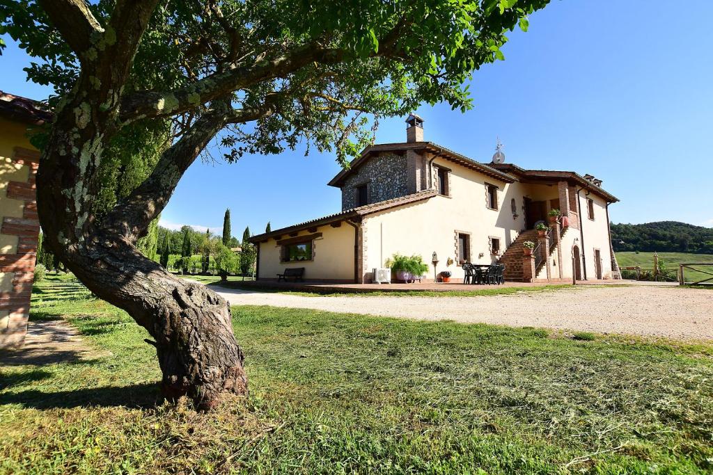 Una casa vieja con un árbol delante. en Il Collicello en Narni