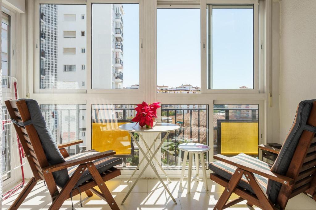 een kamer met 2 stoelen, een tafel en ramen bij Apartment Acapulco in Fuengirola