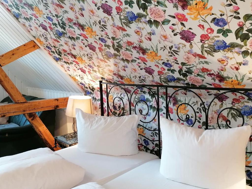 1 dormitorio con pared de flores y 1 cama con 2 almohadas en Pension Pfefferstübchen, en Brotterode