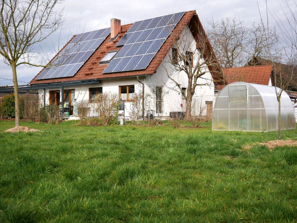 une maison avec des panneaux solaires sur le toit et une serre dans l'établissement Ferienwohnung Obere Alm, à Oberkirch