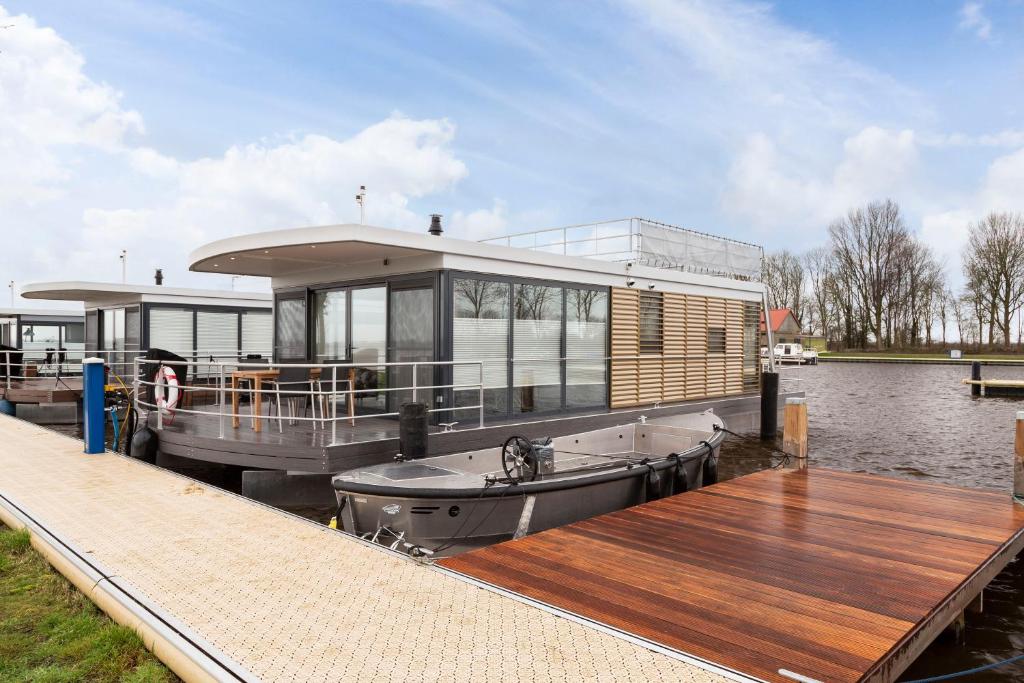 uma casa-barco ancorada numa doca na água em Houseboat 'Elysium' met eigen aanlegsteiger Sneek - Offingawier em Offingawier