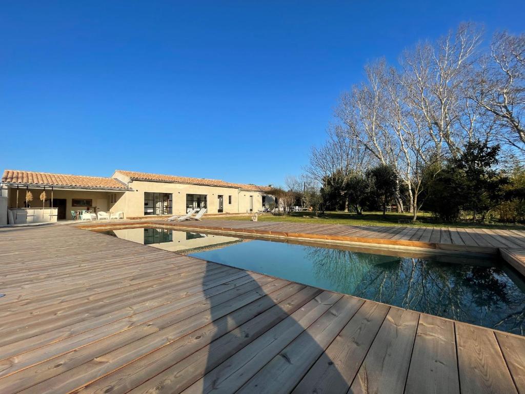 une piscine avec une terrasse en bois à côté d'une maison dans l'établissement La Maison Barbentane, à Barbentane