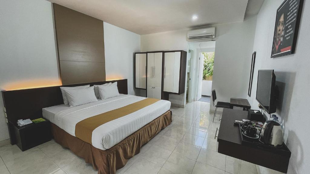 una camera con un grande letto e una televisione di LPP Convention Hotel Demangan a Yogyakarta