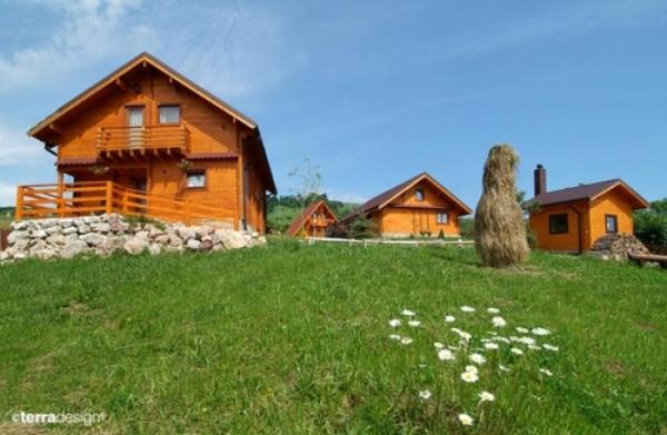 a wooden house on a hill with a field of grass at Pensiunea Ecosasu in Gura Humorului
