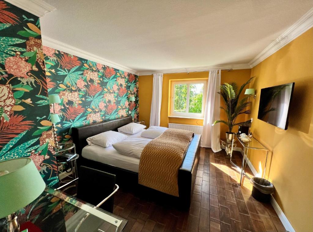 Hotel Ashley's Garden في دوسلدورف: غرفة نوم مع سرير وورق جدران