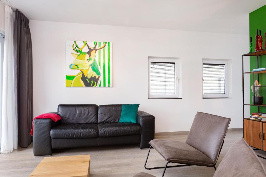 ein Wohnzimmer mit einem Ledersofa und einem Gemälde in der Unterkunft Beneden appartement paviljoenwei 12, Sneek - Offingawier in Offingawier