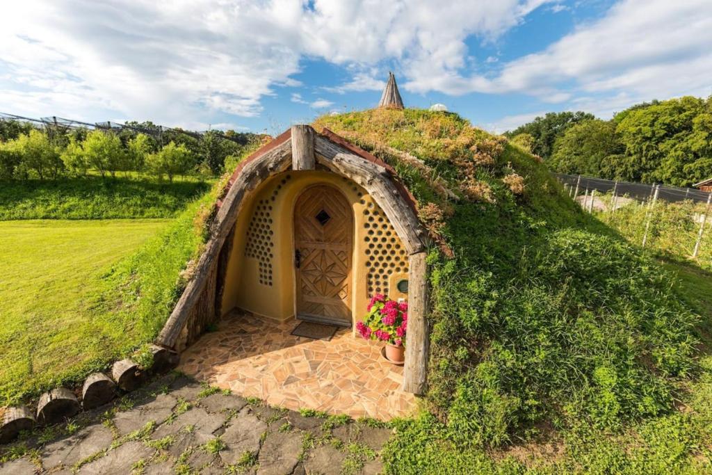 a small house with a grass roof with flowers at Magical Hobbit's House - Happy Rentals in Ljutomer