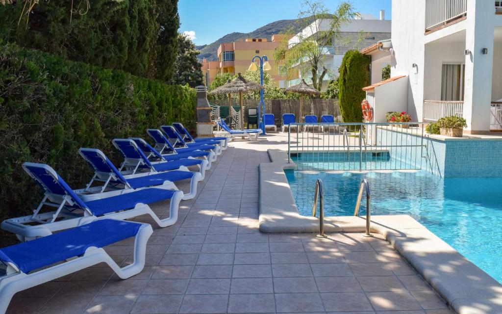 a row of blue lounge chairs next to a swimming pool at Villa Allexia- APARTMENT SOL - Puerto Pollensa in Port de Pollensa