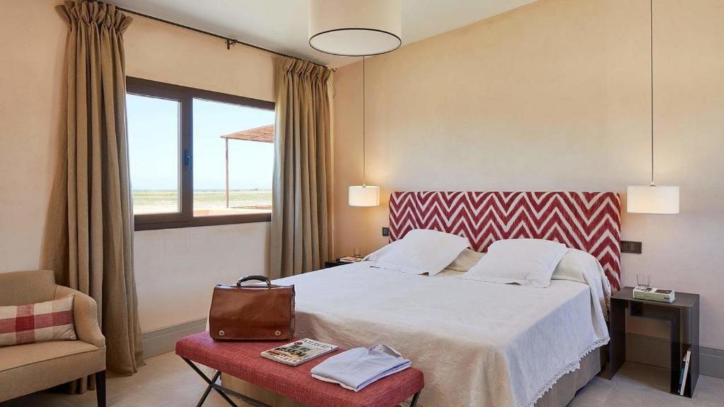 a hotel room with a bed and a chair and a window at Trafalgar Polo Club in Vejer de la Frontera