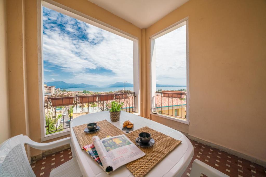 デセンツァーノ・デル・ガルダにあるGardappartamenti Cavour Lake Viewのテーブルと大きな窓が備わる客室です。