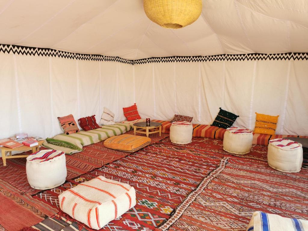 a room with a tent with couches and tables at Bivouac Erg Chegaga Nomademoi in El Gouera