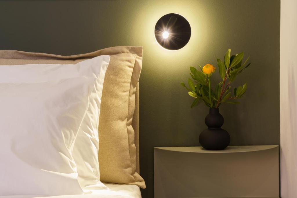 a bed with a pillow and a vase with a plant at Vagabond Guesthouse in Athens