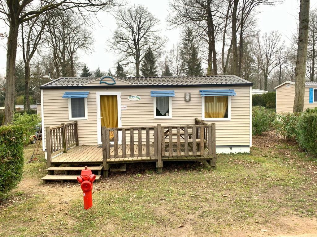ein kleines Haus mit einer Veranda und einem roten Hydranten in der Unterkunft Mobil Home 6 personnes in Saint-Chéron