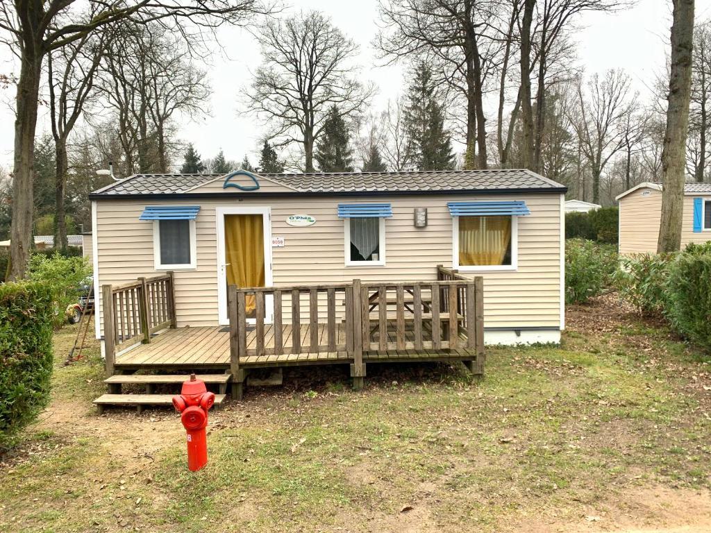 une petite maison avec une terrasse couverte et une bouche de feu rouge dans l'établissement Mobil Home 6 personnes, à Saint-Chéron