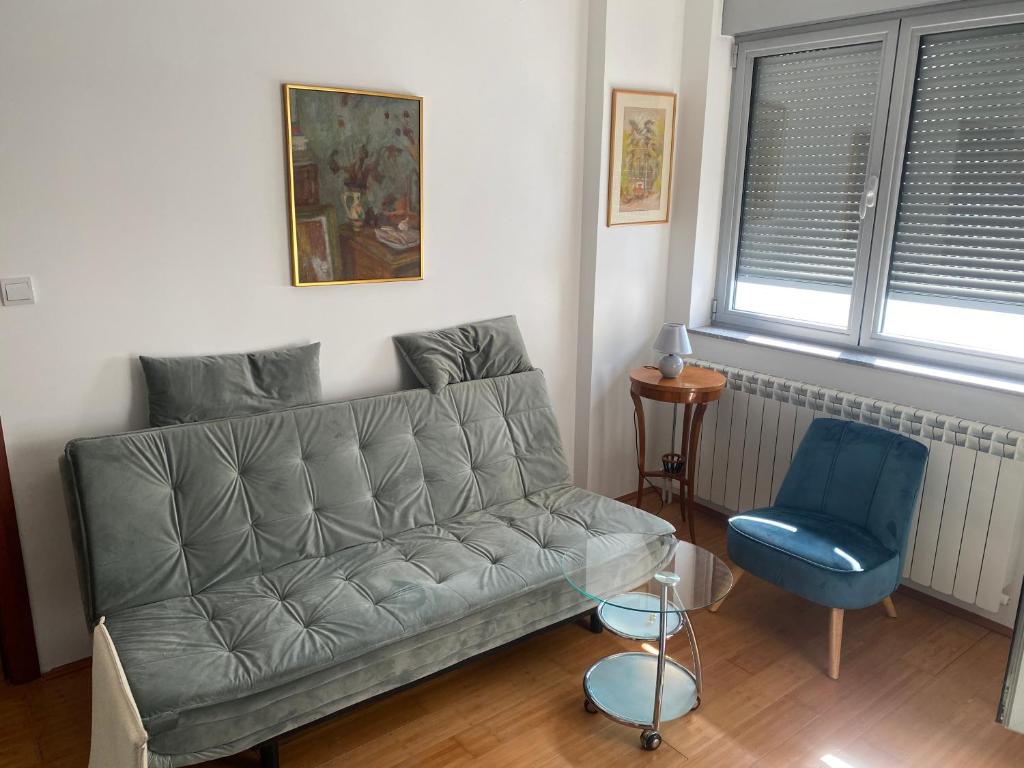 a living room with a couch and a blue chair at Sofy Center Apartment (Free Parking) in Novi Sad