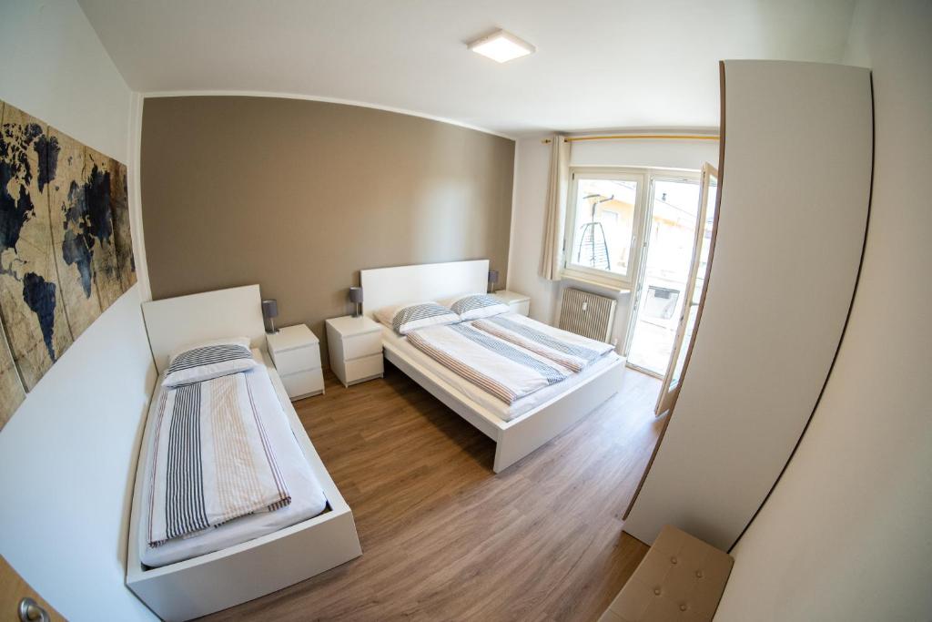 a small room with two beds and a window at Flow Apartments Wolkenstein in Merano
