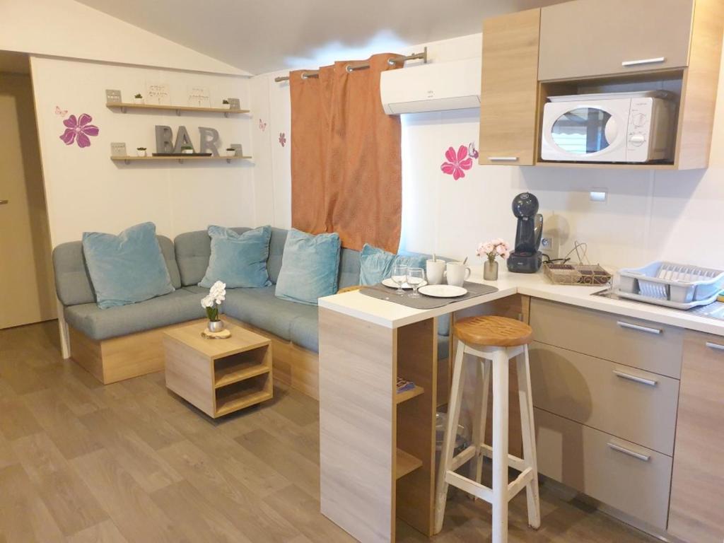 a living room with a blue couch and a kitchen at MOBILHOME 3CH LAVE LINGE - EXT COCOONING ES117 in Fréjus