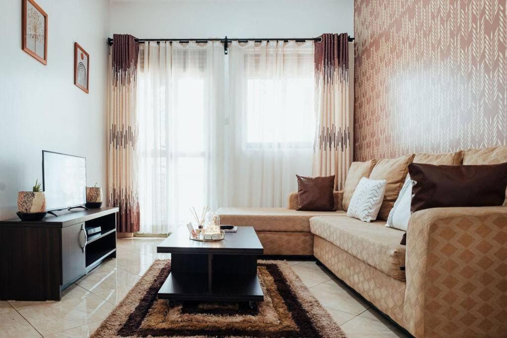 uma sala de estar com um sofá e uma mesa em Umusaale 2BR1B em Kampala
