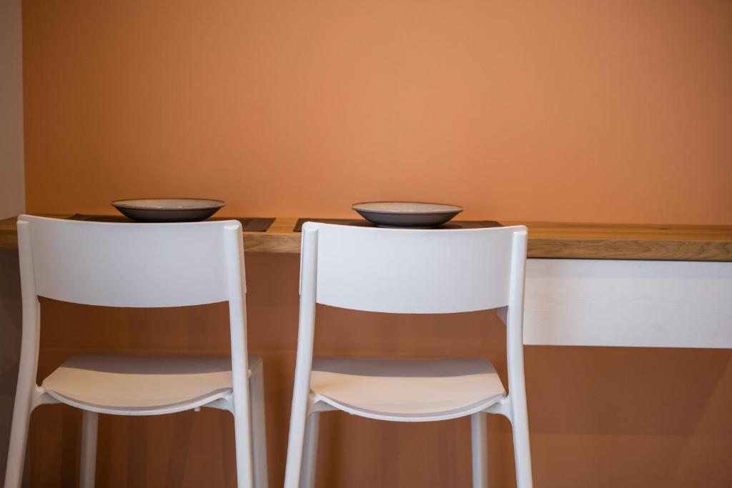 two white chairs sitting at a table with orange walls at Vagabond Guesthouse in Athens