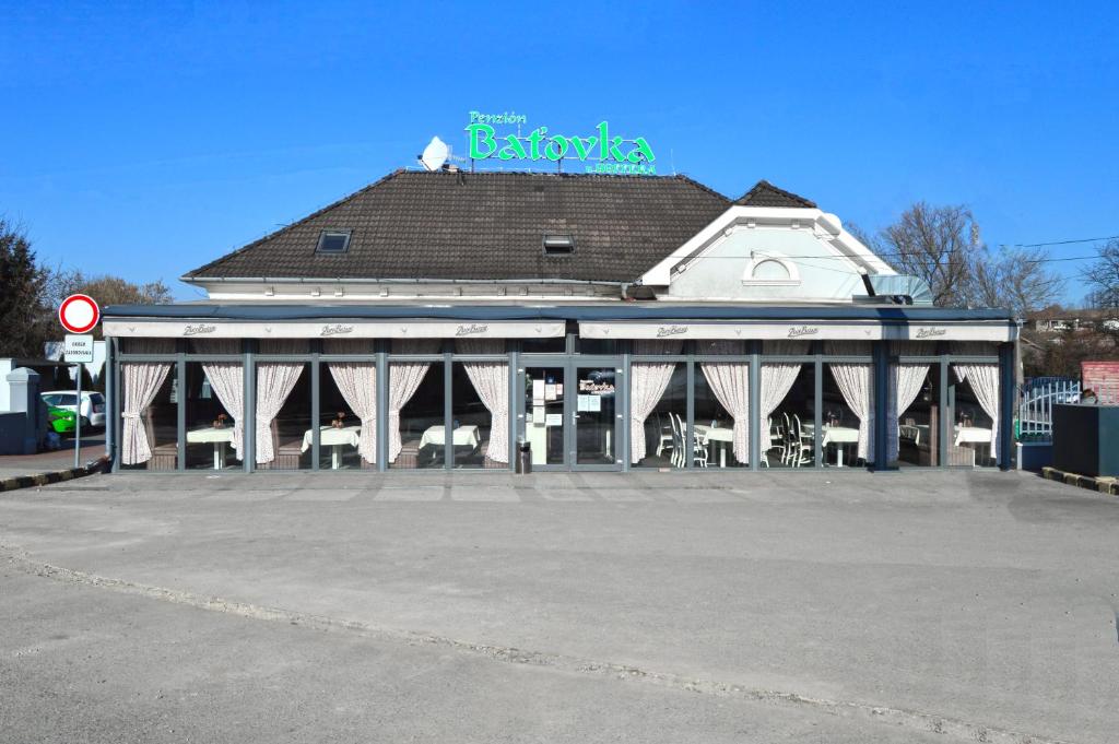 a large white building with a sign on top of it at Penzion Batovka u Hoffera in Partizánske