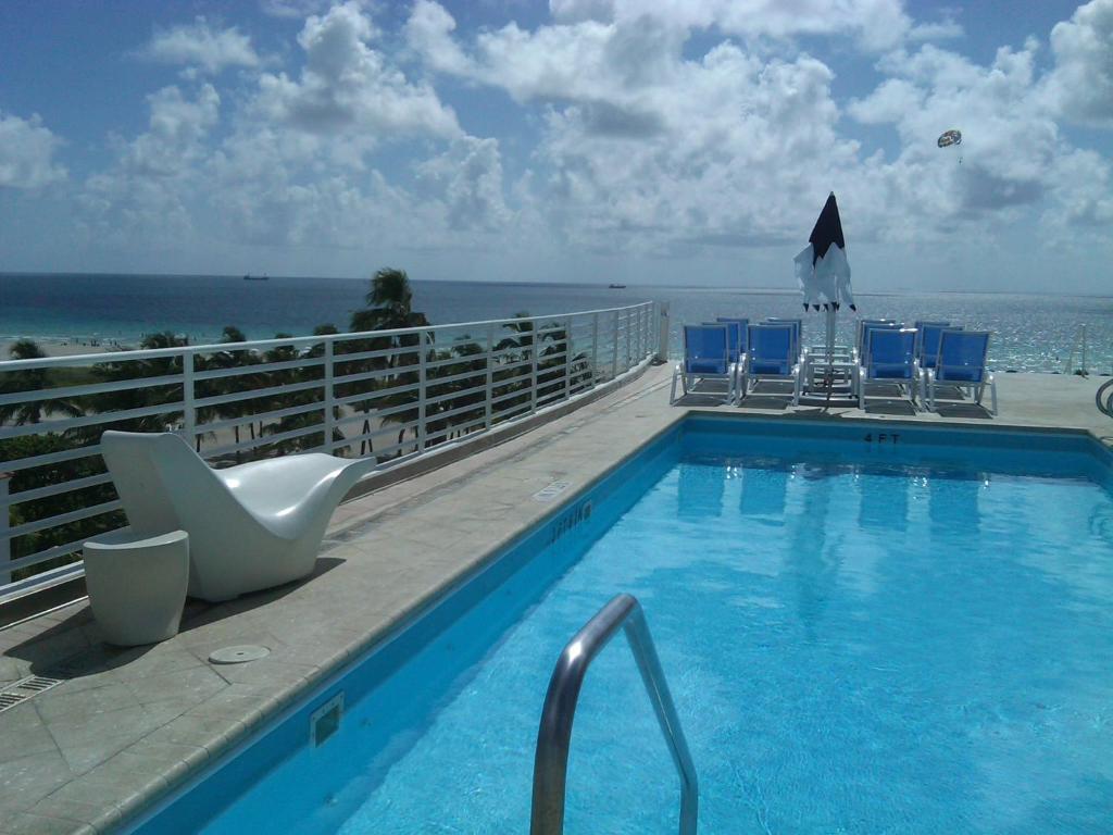 una piscina con sillas y el océano en el fondo en Strand Ocean Drive Suites en Miami Beach