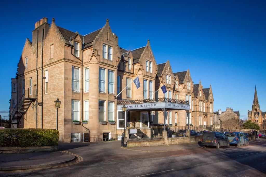 愛丁堡的住宿－The Bruntsfield Hotel，一座大型砖砌建筑,前面有汽车停放