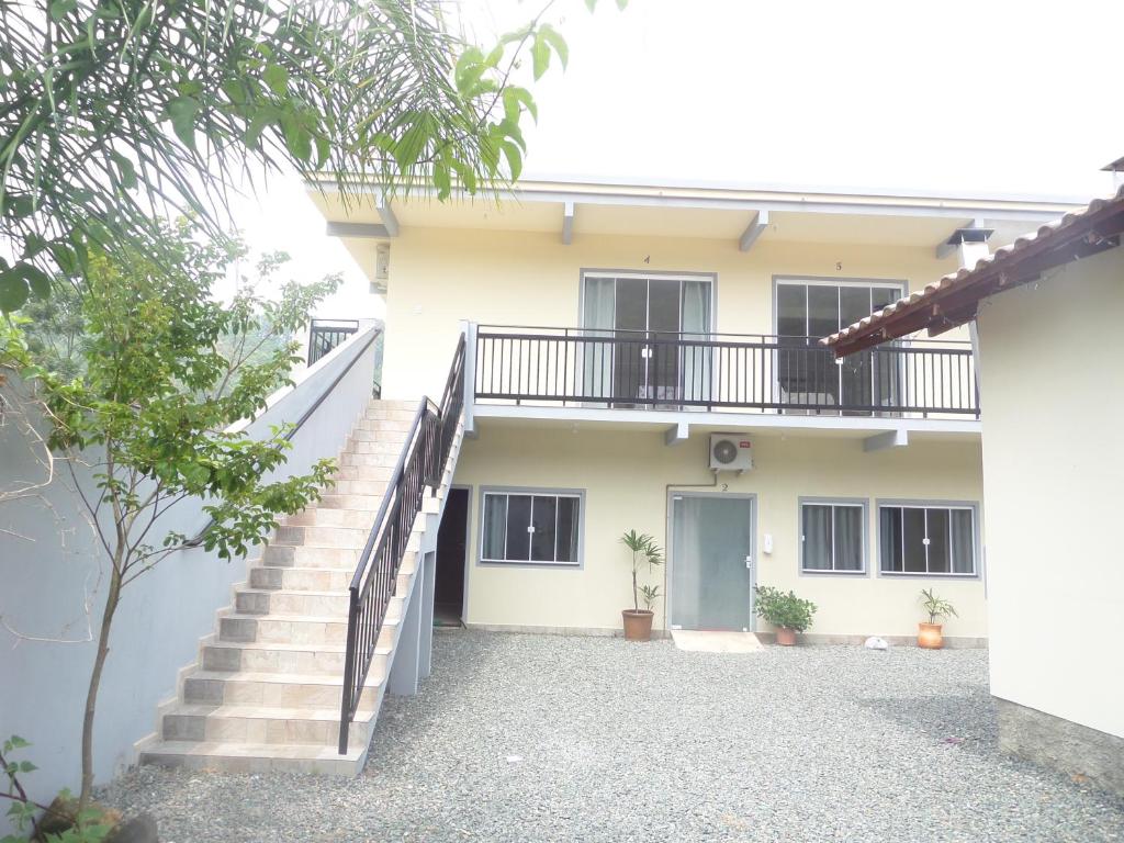 a white house with stairs and a balcony at Pousada Casa Verde in Penha