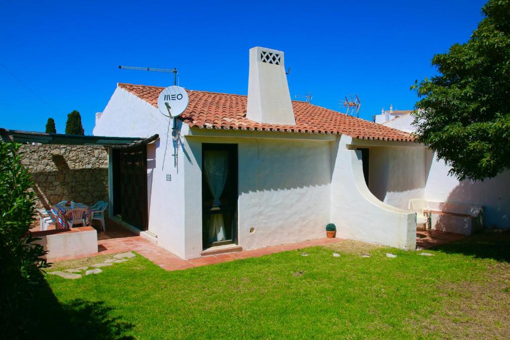 ein kleines weißes Haus mit einem Rasenhof in der Unterkunft Villa Jacaranda - 550m from the beach - Free WIFI - By Bedzy in Albufeira