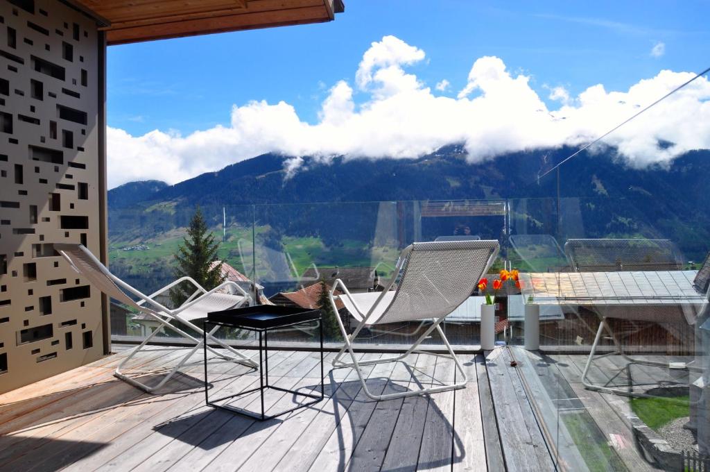 a balcony with chairs and a table and a mountain at Panoramic Ecodesign Apartment Obersaxen - Val Lumnezia I Vella - Vignogn I near Laax Flims I 5 Swiss stars rating in Vella