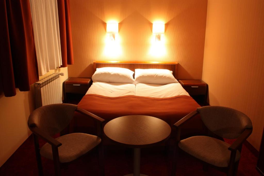 a small bedroom with a bed and two chairs at Impresja in Borek Wielkopolski