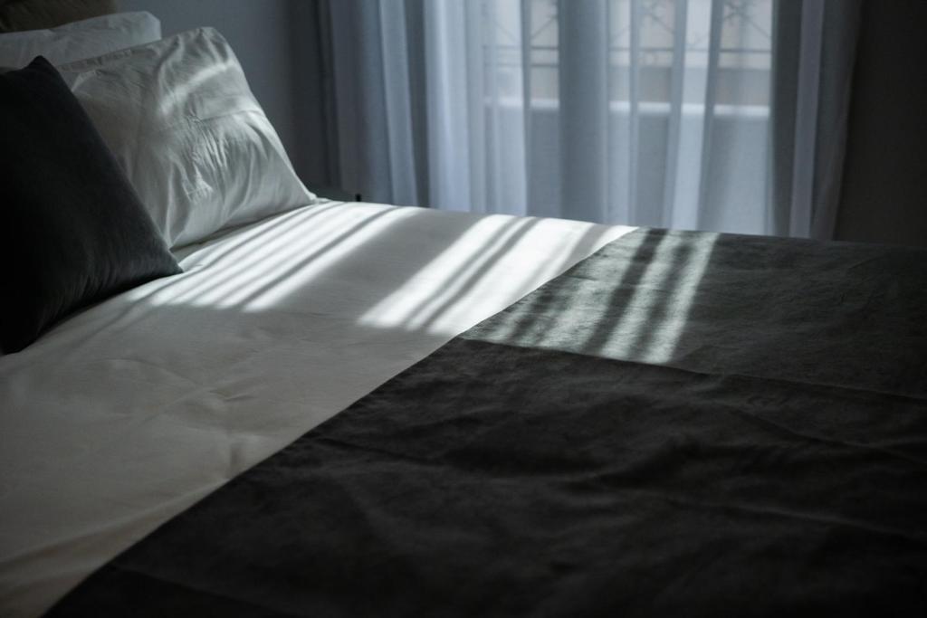 a bed with a black and white blanket and a window at Vagabond Guesthouse in Athens