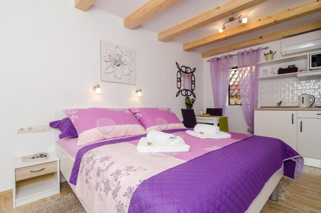 a bedroom with a purple bed with towels on it at Lavender Garden Apartments in Dubrovnik
