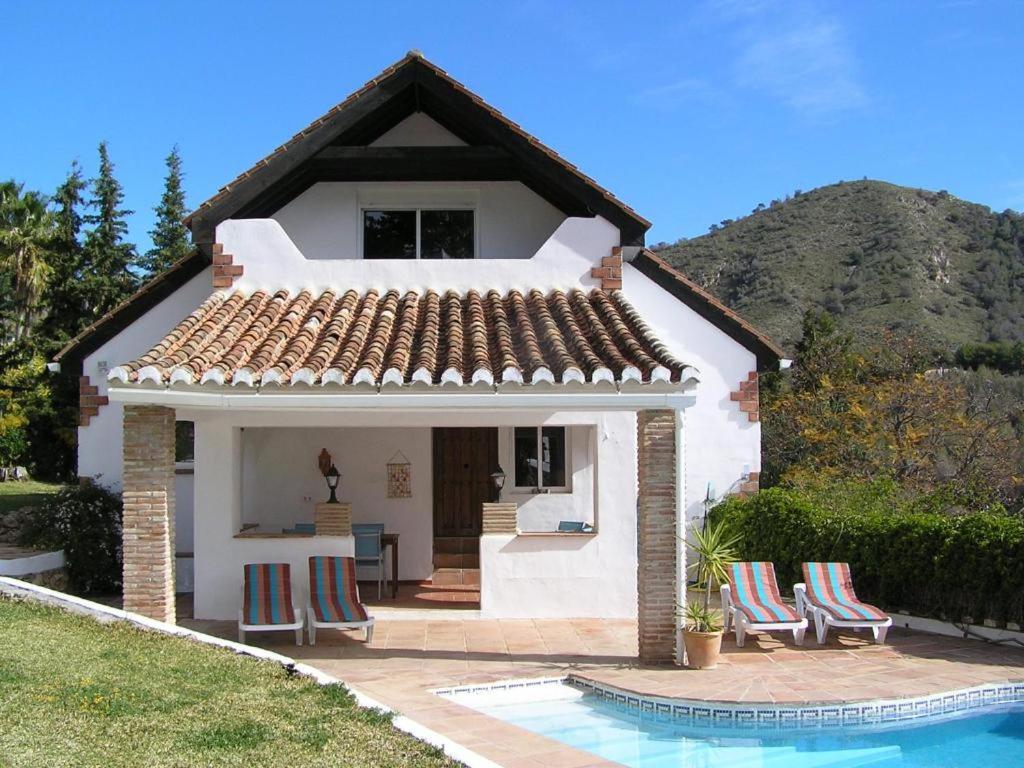 a small white house with chairs next to a pool at Villa Morera Garden Villa 5 pers, 2 bedrooms with extra rooms when needed in Frigiliana