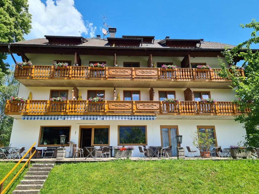 un edificio con balcón con mesas y sillas en Hotel Carossa bed&breakfast, en Sankt Gilgen