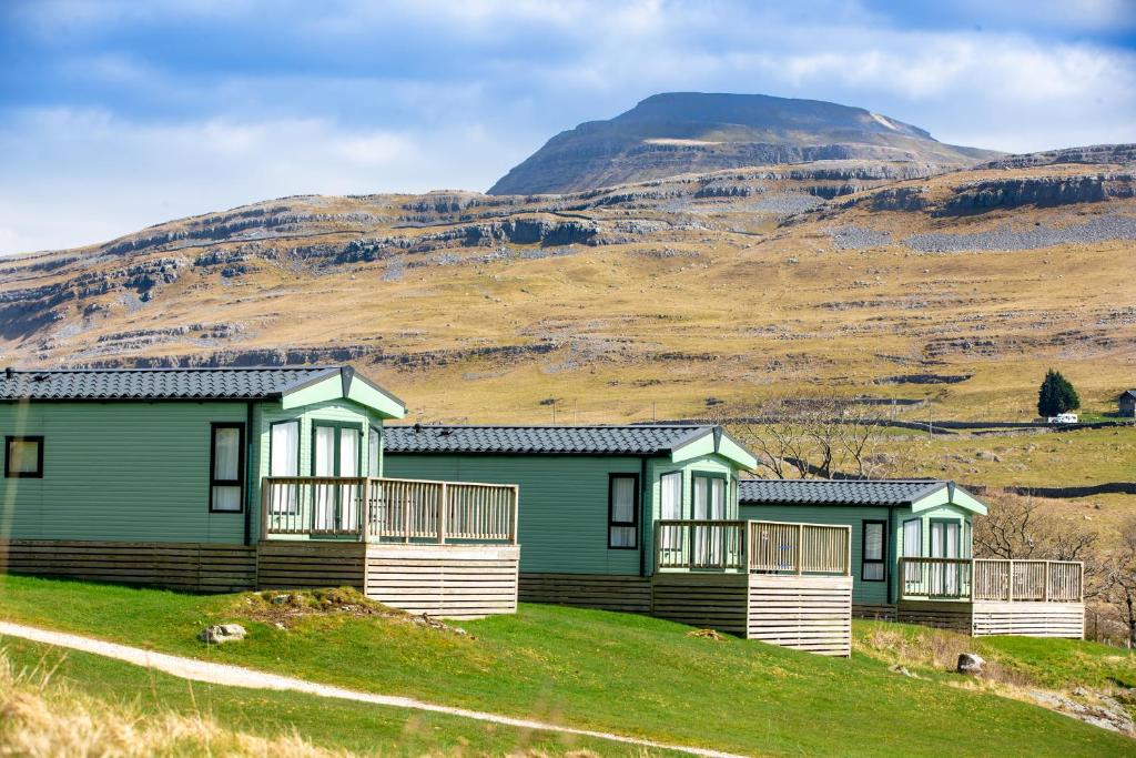 a row of houses on a hill with a mountain in the background at Falls Park in Ingleton 