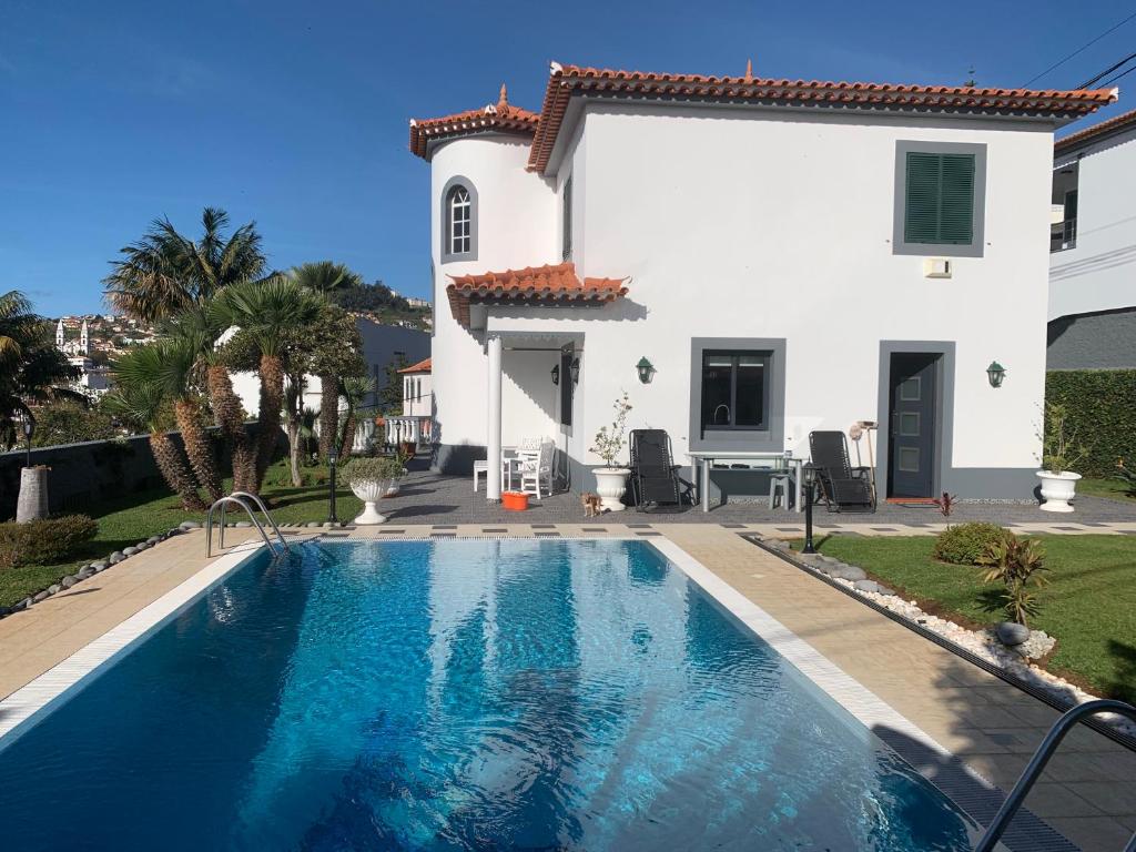 a villa with a swimming pool in front of a house at Beautiful 1-Bed Apartment in Funchal Madeira in Funchal