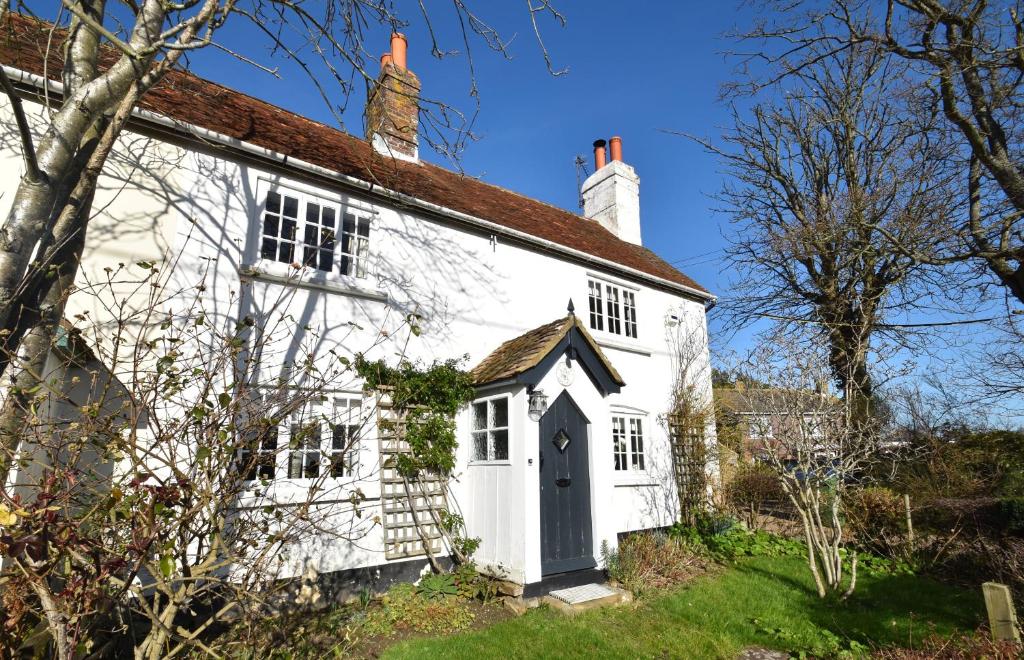 an old white cottage with a black door at Rose Mullion Cottage in Pett