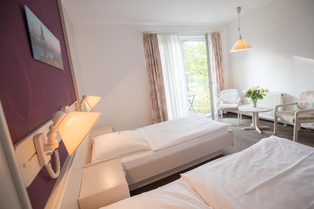 1 dormitorio con 2 camas y sala de estar con mesa. en Hotel Heidenauer Hof, en Heidenau