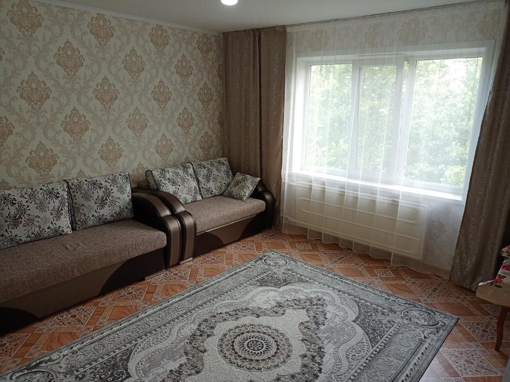 a living room with a couch and a window at Апартаменты на Первомайская 37 "А" in Semey