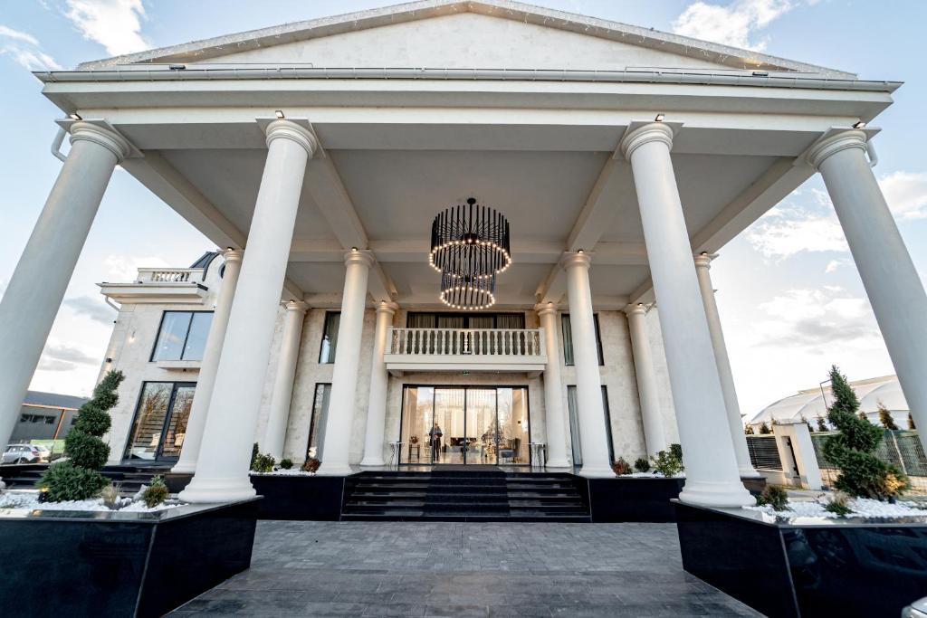 a large white building with columns and a chandelier at Hotel Caprice in Bacău