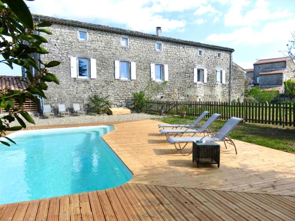 a pool with chairs and a house in the background at Gite Mas Sophia in Labeaume
