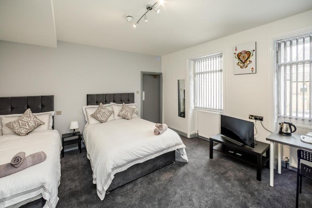 a bedroom with two beds and a flat screen tv at Huddersfield Central Lodge in Huddersfield