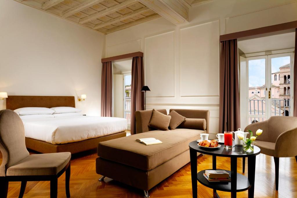 a hotel room with a bed and a couch and a table at Splendor Suite Rome - Suites & Apartments in Rome