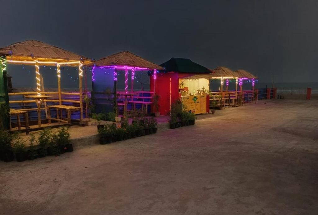 a row of tables and umbrellas on the beach at night at Resort Garden Retreat Seaview in Mandarmoni