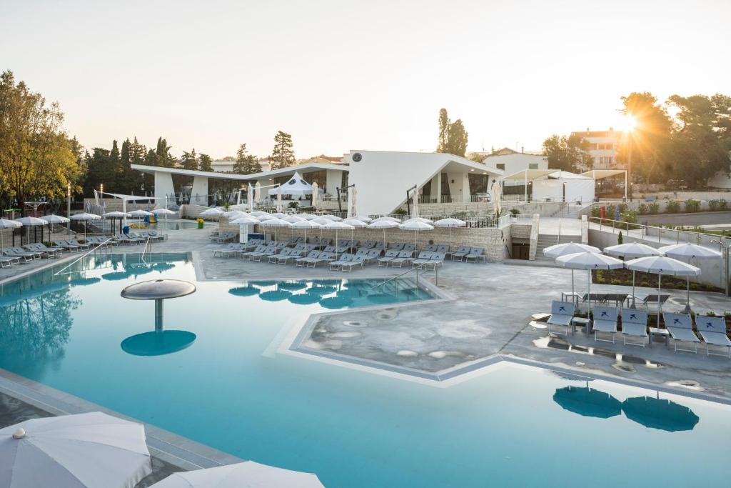 a large swimming pool with chairs and umbrellas at Falkensteiner Premium Mobile Homes and Camping Zadar in Zadar