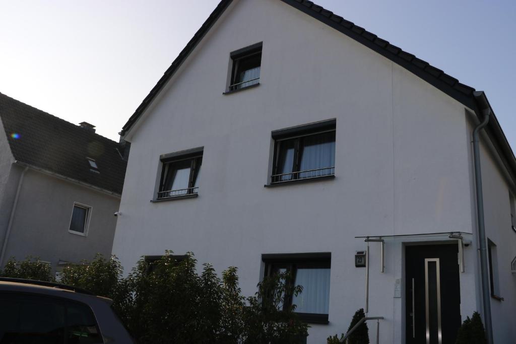 a white house with black windows and a car at Rooms in Düsseldorf near the Airport/Fair in Düsseldorf