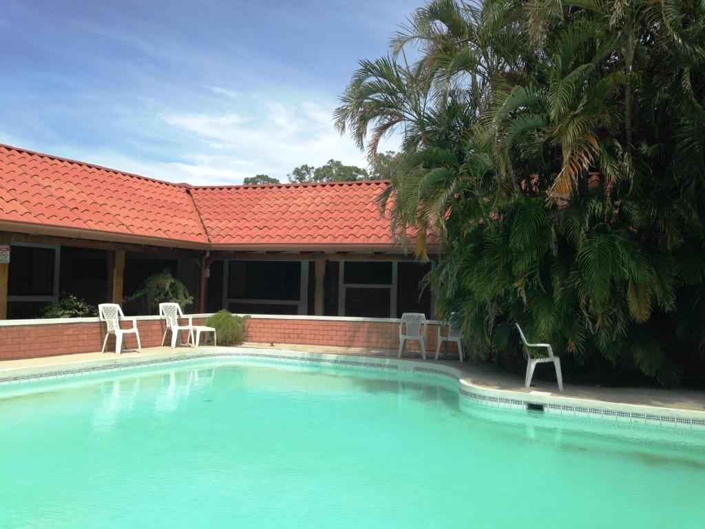 a swimming pool with two chairs and a house at Hotel El Bramadero in Liberia