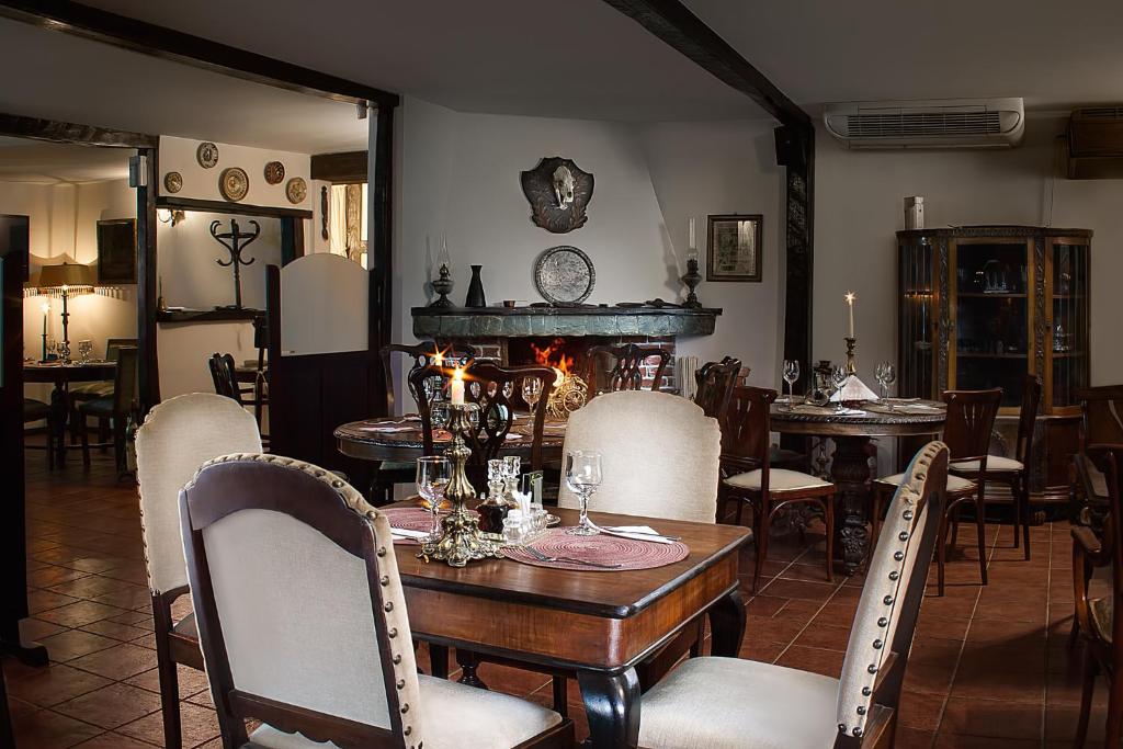 een eetkamer met een tafel en stoelen en een open haard bij Pensiune-Restaurant Tara Luanei in Sărata-Monteoru