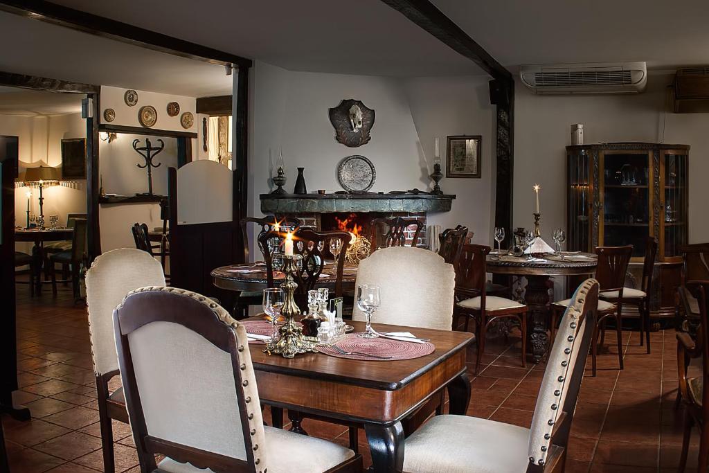 a dining room with a table and chairs and a fireplace at Pensiune-Restaurant Tara Luanei in Sărata-Monteoru